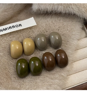 Vue détaillée de boucles d'oreilles ovales en résine sur une texture en fausse fourrure beige