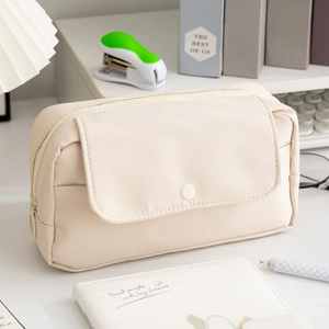 Dettaglio dell'astuccio beige in tela con tasca a patta su una scrivania organizzata