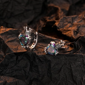 Macro view of silver crown heart earrings featuring iridescent zircon stones on dark paper