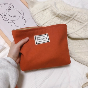 Close-up of bright orange cotton clutch with Time To Party label and metal zipper