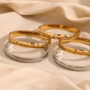 Detail of gold and silver starburst bangles with cubic zirconia on beige silk fabric