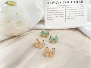 Detailed macro view of pink and blue enamel bow earrings with elegant golden base