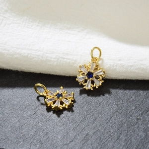 Detailed macro view of golden snowflake charms with blue gemstone and clear zircon accents
