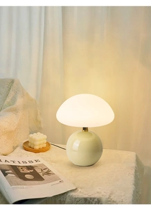 Detail of mushroom lamp with creamy white dome shade and round ceramic base on a soft tablecloth