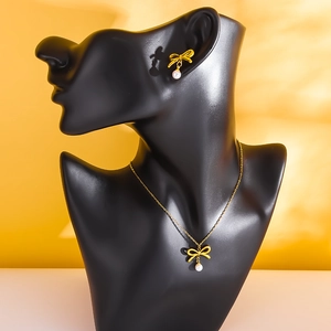Parure collier nœud doré et boucles d'oreilles perles sur buste de présentation