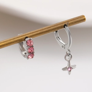 Detailed shot of asymmetric silver earrings with pink zircon cross pendant and wide hoop