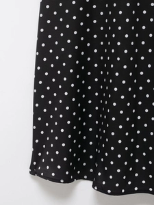 Detailaufnahme von schwarzem Stoff mit weißen Punkten und elegantem Faltenwurf