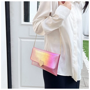 Close-up of pink laser heart pendant envelope wallet with golden chain on model