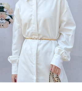 Detail of gold metal elastic waist chain with diamond encrusted buckle on white dress