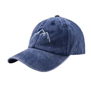Detailed close-up of white mountain embroidery on washed navy blue cotton baseball cap