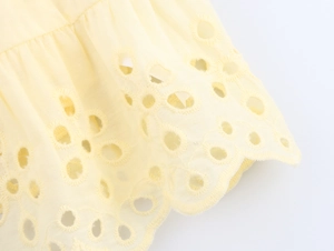 Macro detail of intricate floral eyelet embroidery and layered ruffle on poplin cotton