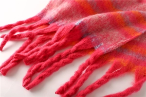 Close-up of vibrant red, orange and blue plaid scarf with twisted tassel fringe detail