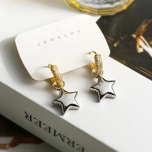 Detailed shot of asymmetric gold earrings with crystal inlay and silver star pendant