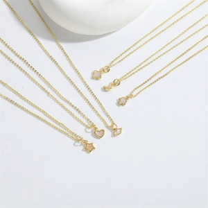 Minimalist gold necklaces with heart star and moon shell pendants on white ceramic