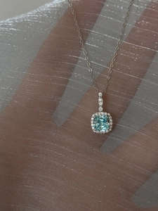 Macro view of blue square halo pendant necklace with sparkling diamonds on silver chain