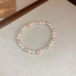 Detail shot of multicolor freshwater pearl bracelet on linen with a Thank You card