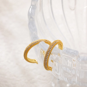 Detailed close-up of 18K gold-plated hoop earrings with micro-set zircon on glass