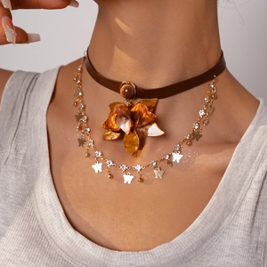Detailed view of layered necklace with amber resin flower and gold butterfly charms