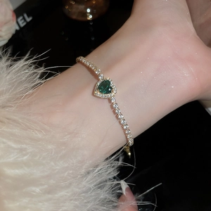 Close-up of heart-shaped green emerald bracelet with micro-pave diamonds on model's wrist