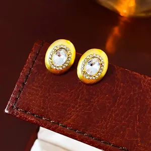 Elegant gold oval stud earrings with large central zircon and brushed metal finish