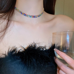 Dettaglio ravvicinato di un collier girocollo con strass multicolore indossato da una modella