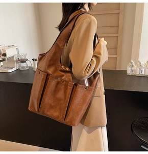 Detailed side view of a brown PU leather tote bag featuring triple front pockets