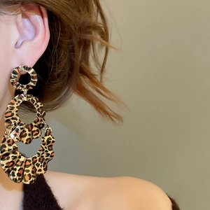 Detail of leopard print layered hoop earrings with golden texture on a female model