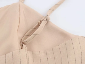Détail macro de la fine bretelle réglable avec boucle argentée sur robe beige rayée