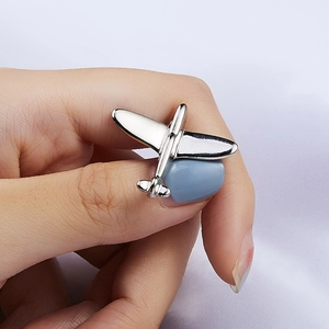 Polished silver alloy airplane brooch badge shown on hand with purple silk background