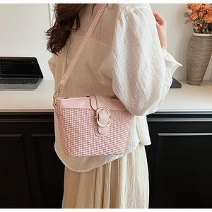 Detailed close-up of pink woven PU leather underarm bag with gold metal buckle and strap