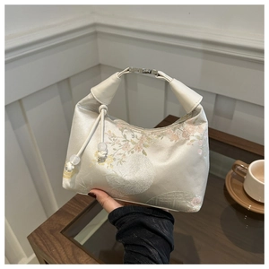 Detail of floral embroidery on a cream Chinese-style silk handbag with leather handle