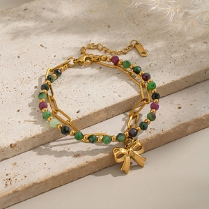Detailed close-up of double-layer gold chain bracelet with colorful beads and bow charm