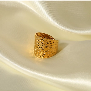 Detailed view of glossy gold hammered texture ring on elegant white silk fabric