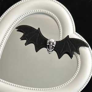 Detail of gothic bat wing hair clip with white skull on beaded heart mirror surface