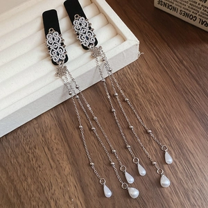 Detail of silver floral earrings with sparkling rhinestones and long pearl tassels