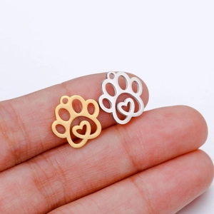 Polished stainless steel paw and heart pendants in gold and silver held on fingertips
