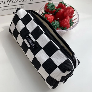 Detail of checkered canvas pencil case with top zipper and black woven logo tag