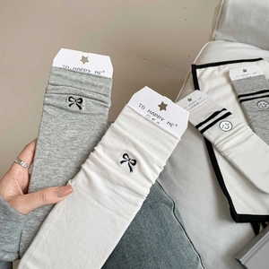 Handheld photo of grey and white cotton crew socks with black bow embroidery