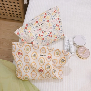 Detail of floral and vintage frame canvas makeup bags with zippers on a soft bed setting