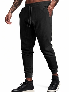 Close-up of black waffle knit fabric texture on men's jogger pants with drawstring waist