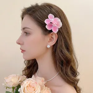 Pink gradient floral hair clip with pearl center worn by model for a summer vacation look