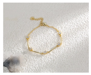 Macro view of gold plated bracelet featuring marquise zirconia and heart pendant detail