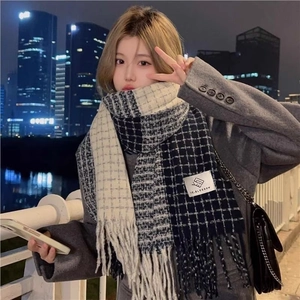 Classic black and white checkered scarf with fringe tassels worn by a model at night