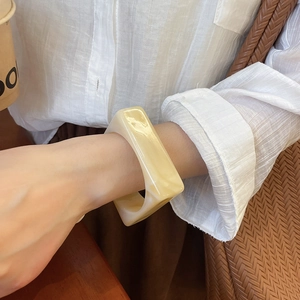 Close-up of a square acrylic bangle with cream marble texture worn by a model