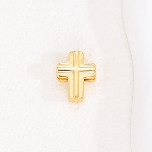 Close-up of golden stainless steel cross pendant with textured relief and metallic finish