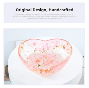 Detailed macro view of heart-shaped resin dish with pink cherry petals and gold foil