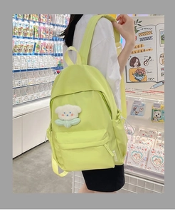 Detail of light green nylon backpack with cute white bear plush charm in a casual setting