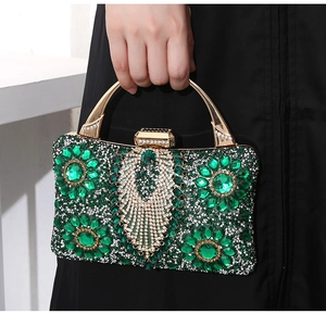 Detailed macro of luxury evening clutch with green marquise gems and gold handle