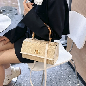 Close-up of cream faux leather handbag with crocodile pattern and vintage bamboo handle