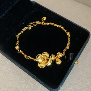 Detailed macro view of 24K gold-plated double-layer chain bracelet with floral charms